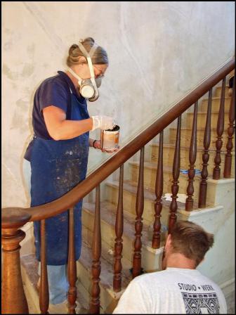 Becky Witsell cleans newel and handrail on walnut and oak stairwell
